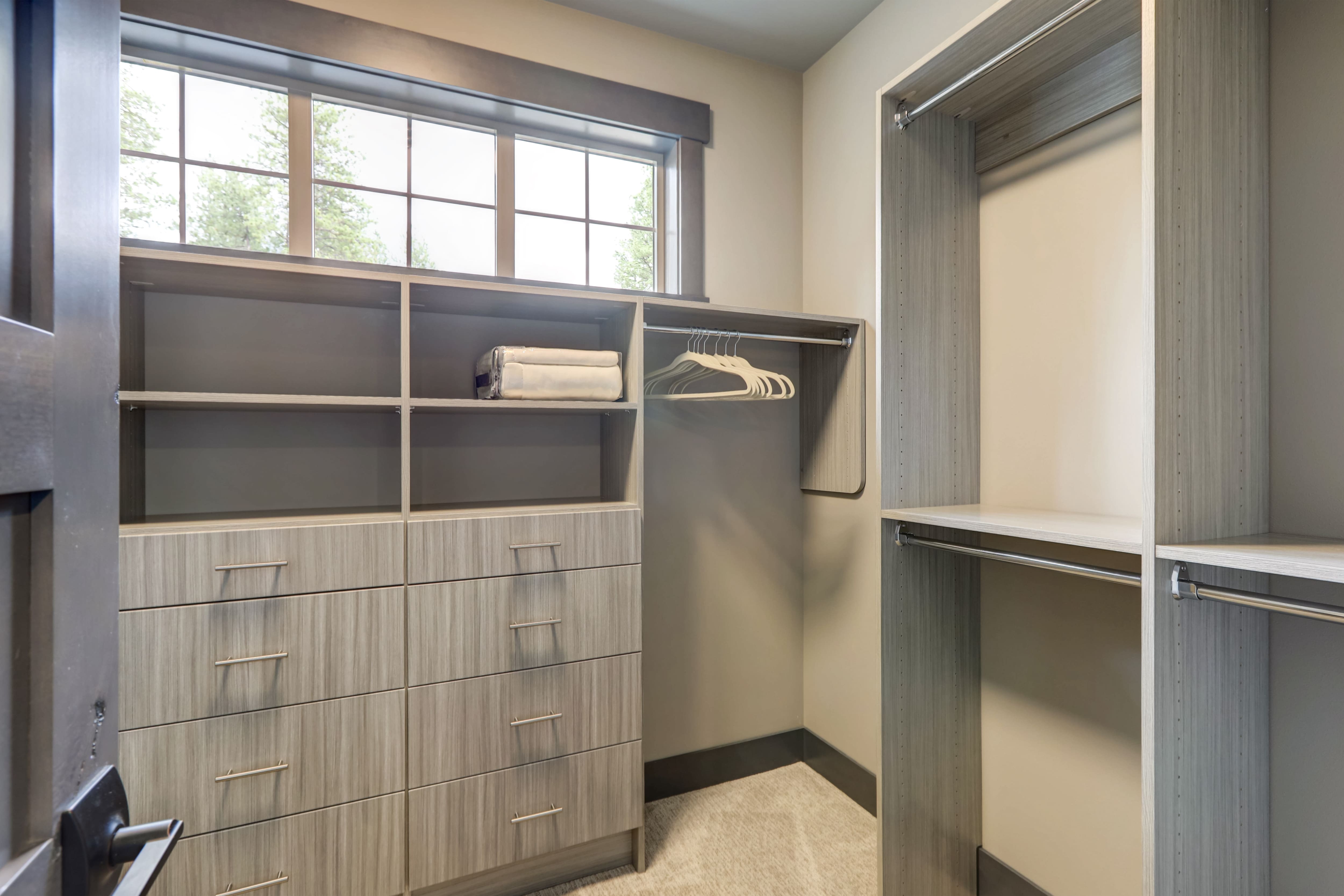 A walk-in closet with gray shelving and a long horizontal window
