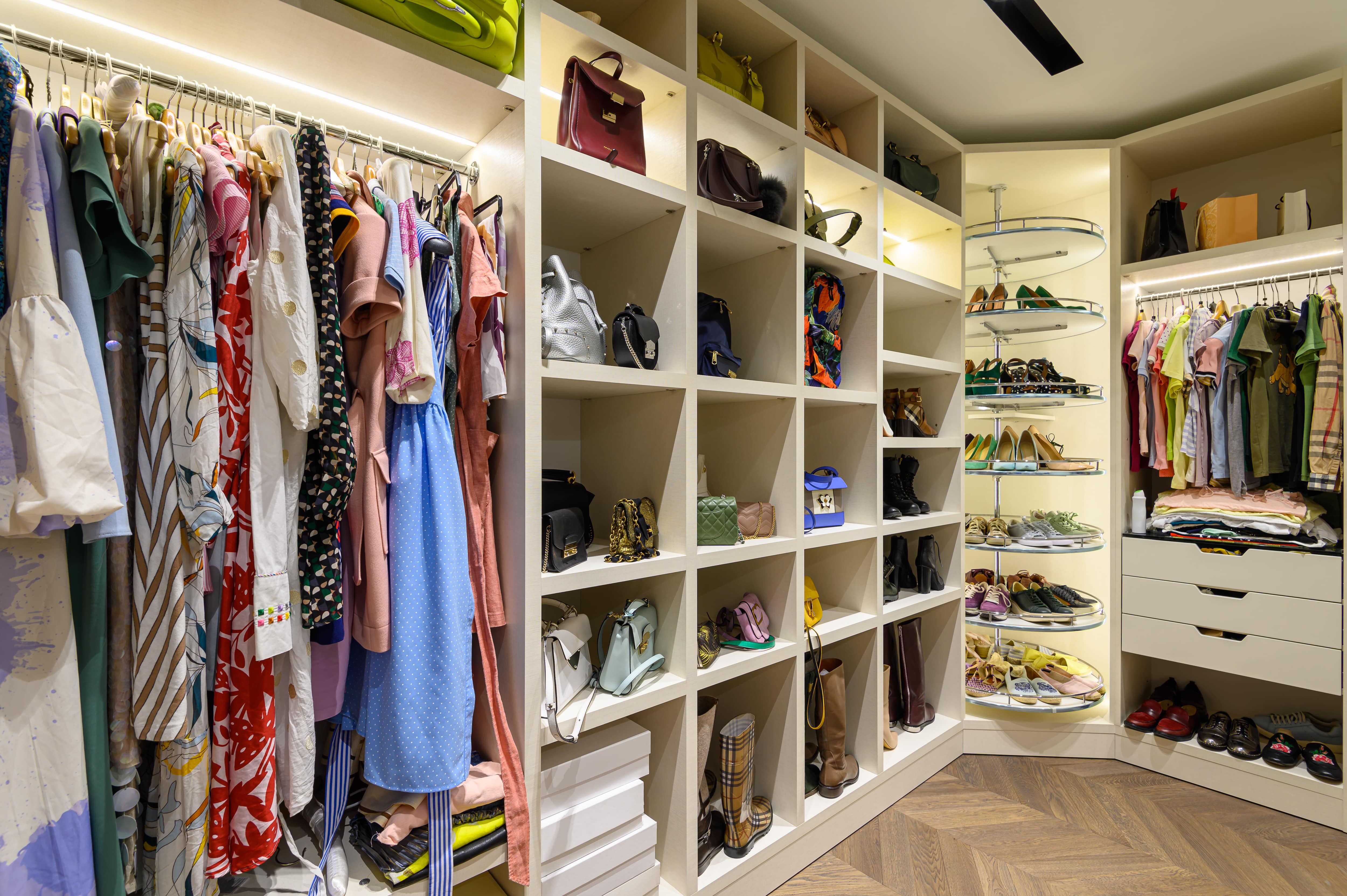A large walk-in closet with a rotating shoe rack in the corner