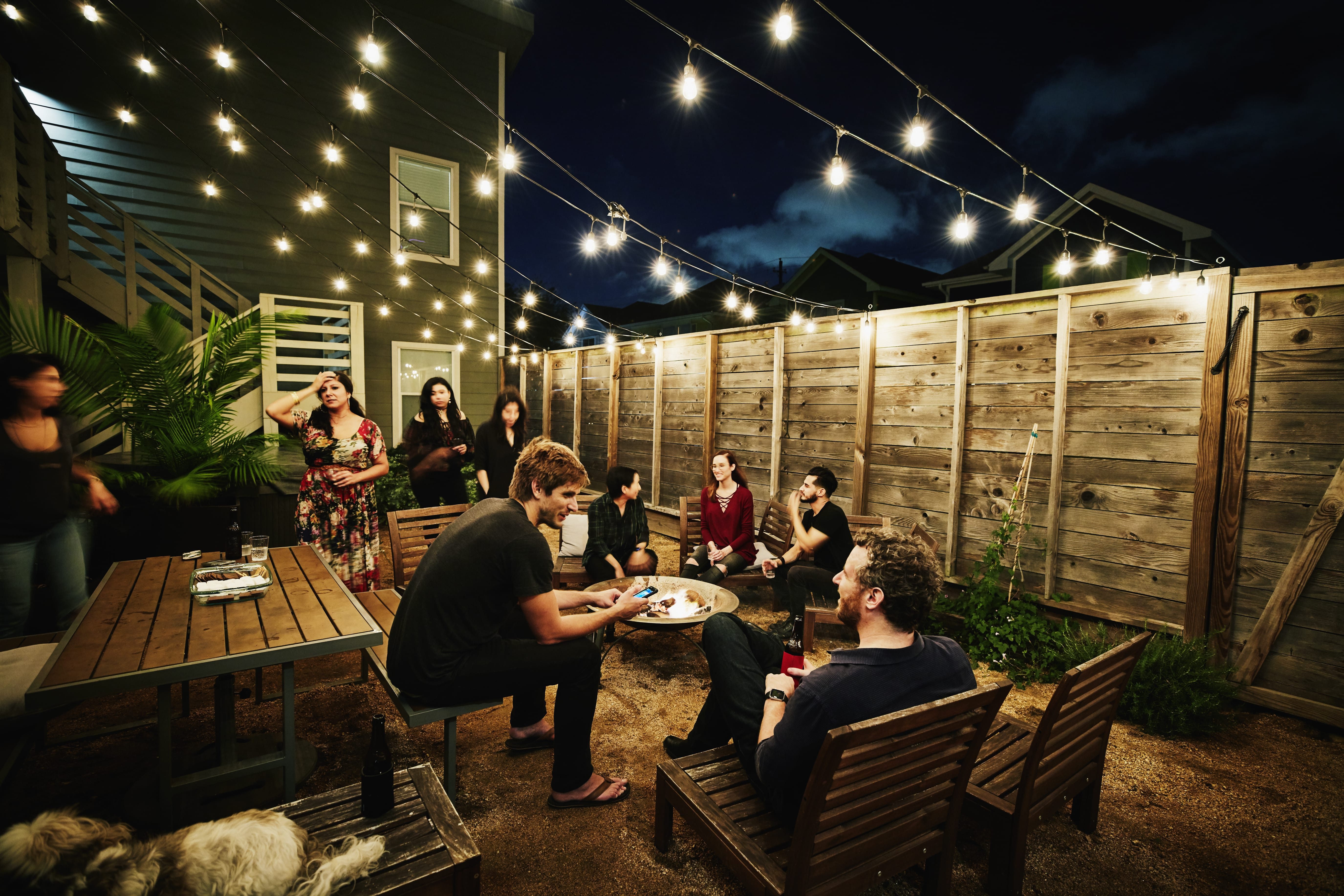 Friends at an outdoor party sitting in front of wooden fence
