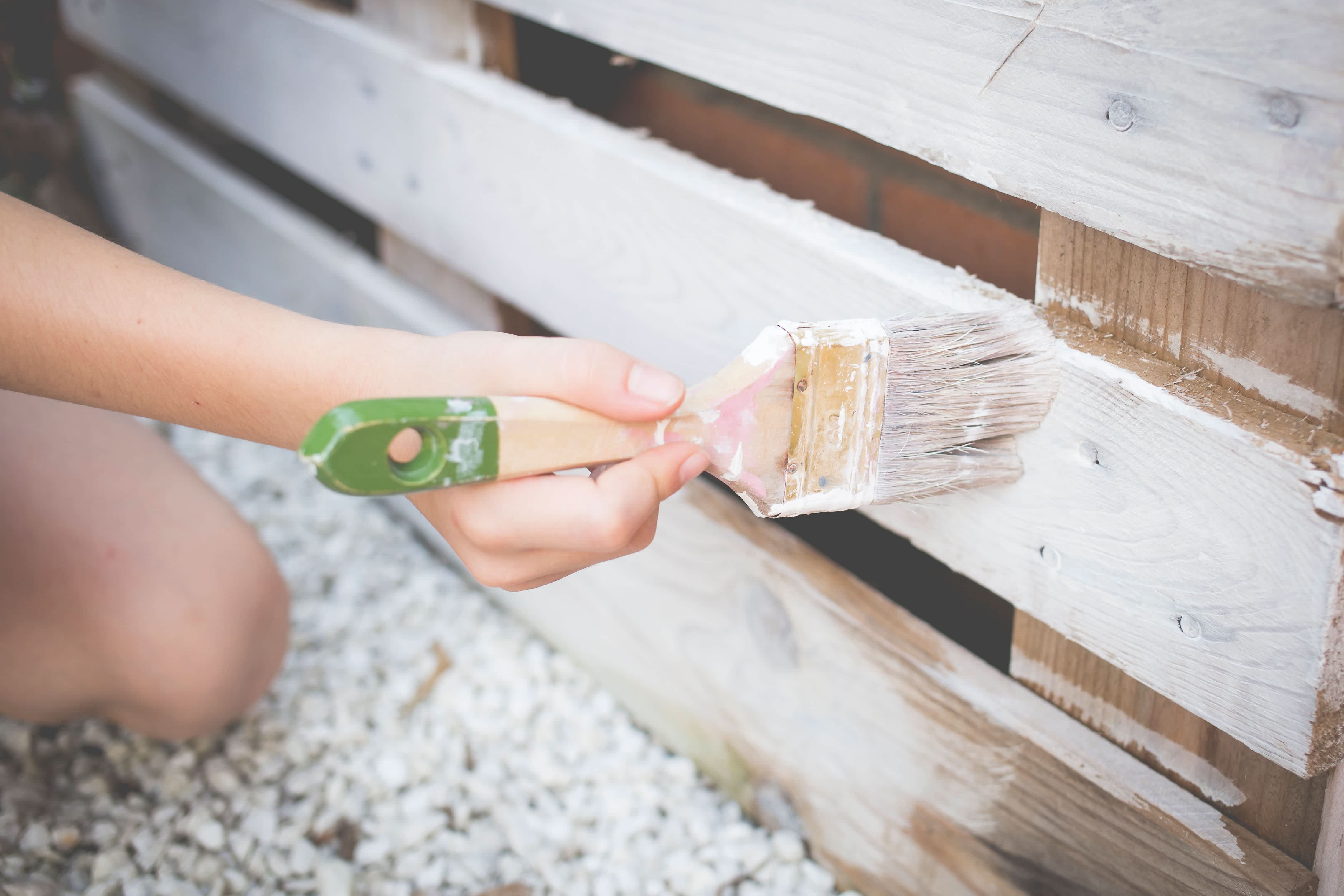 Painting recycled pallet white with paintbrush