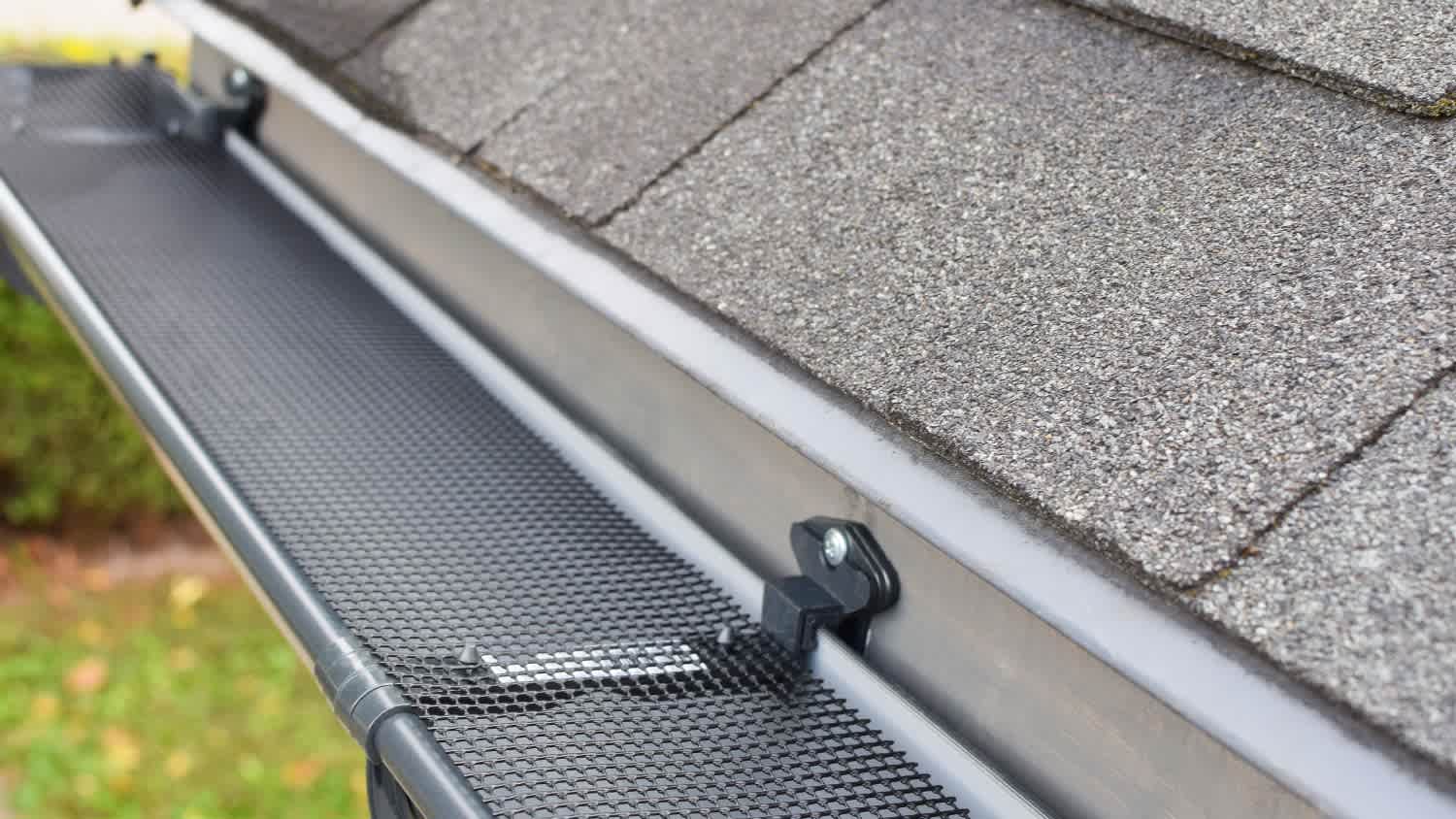 A plastic guard over a dark gray plastic rain gutter