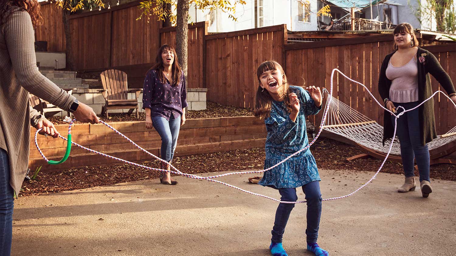 A family jumps rope in a backyard