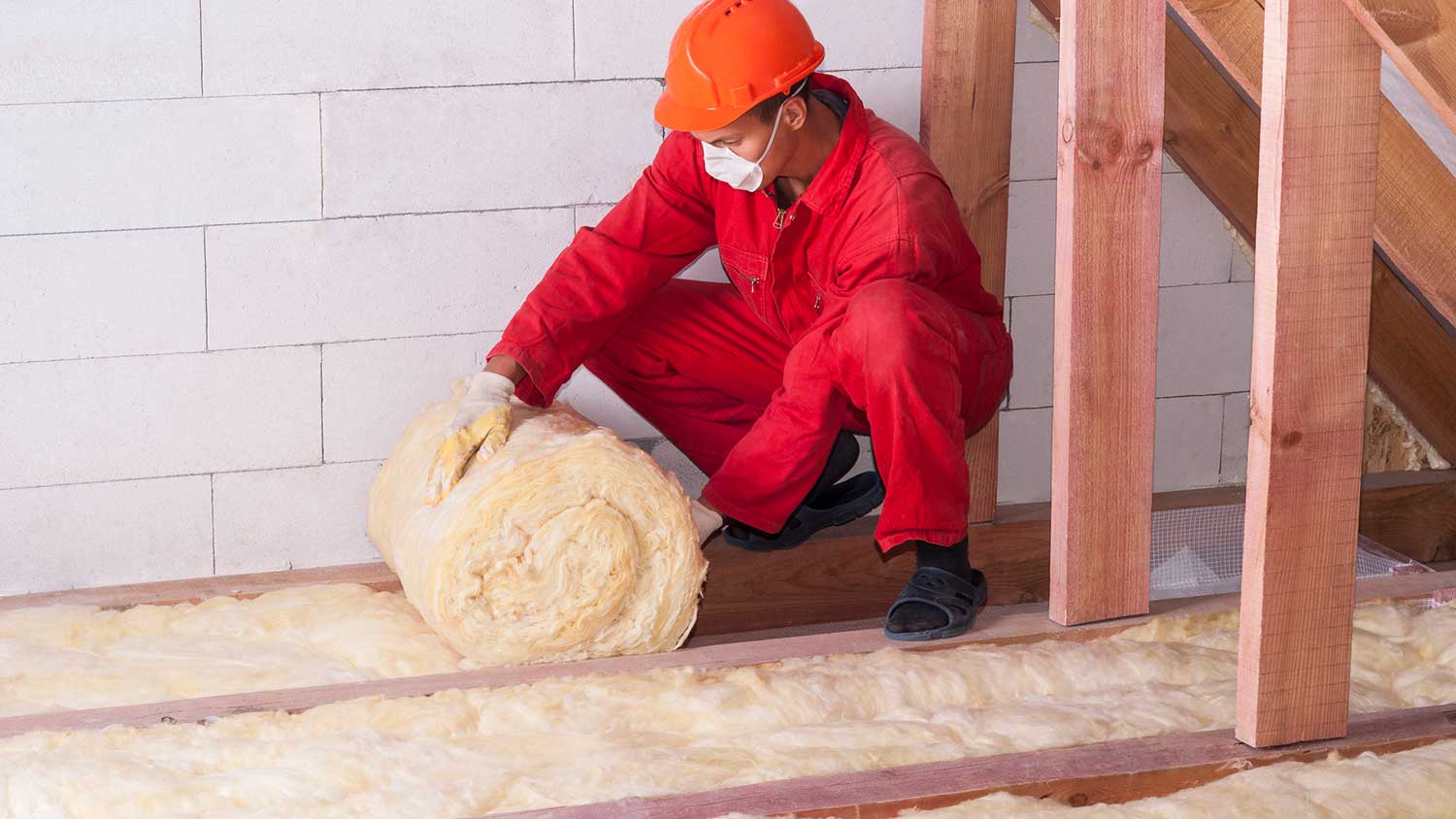 Worker installing attic floor insulation