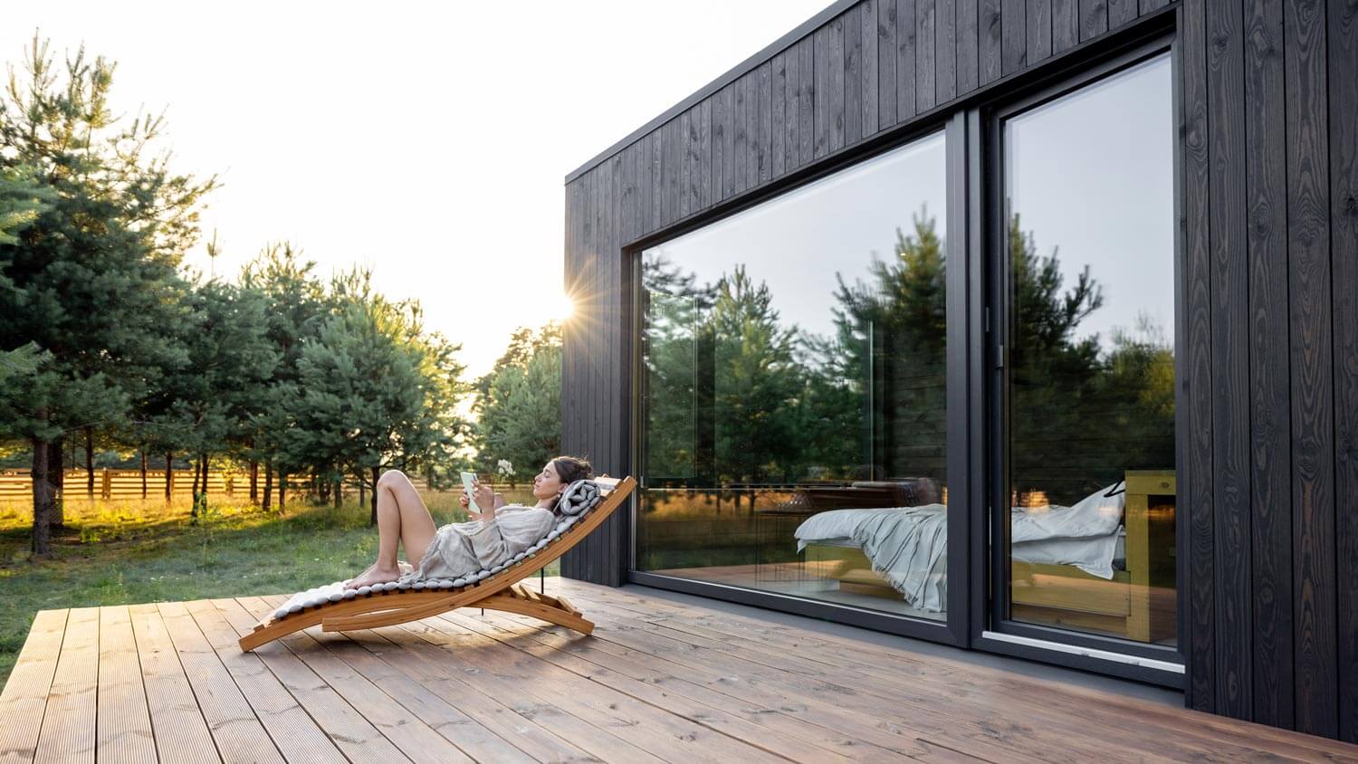 A woman resting on a terrace of a contemporary house next to pine trees