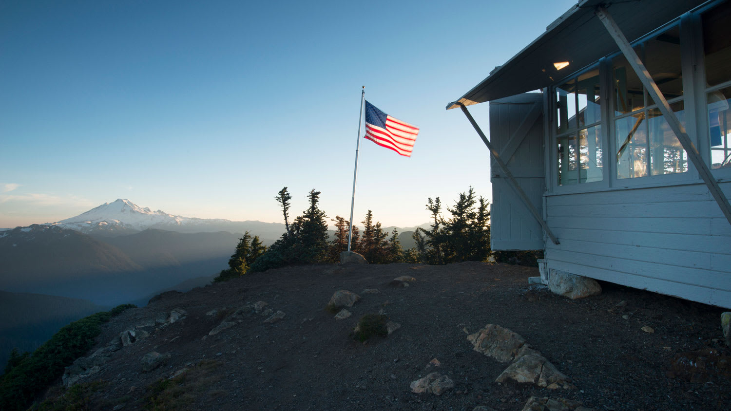 A flagpole with the USA flag on a mountain house