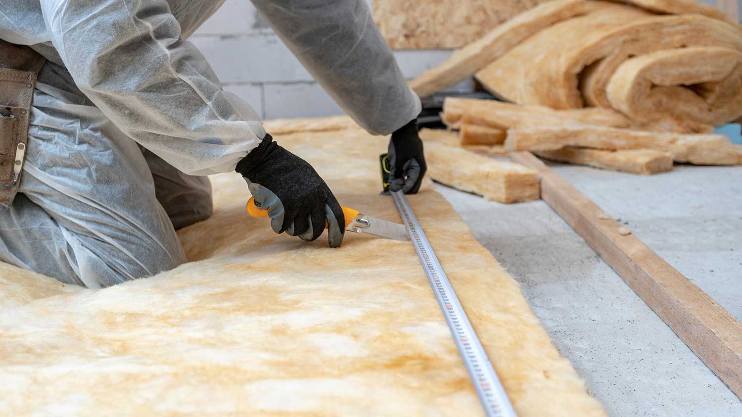 Worker installing rockwool insulation on the floor