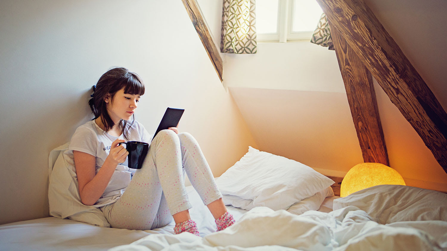 Teen girl reading e-book in her bed