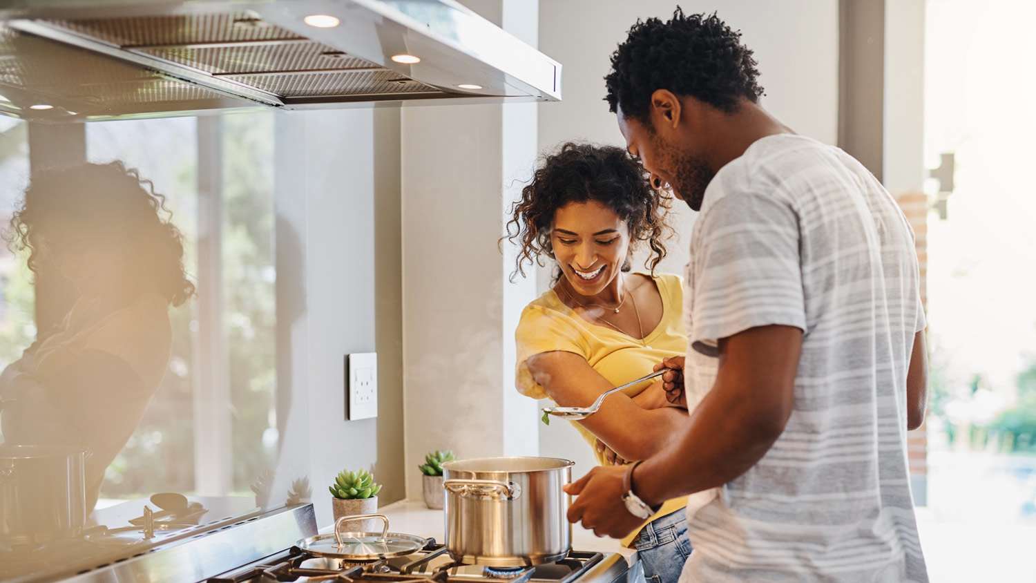 Couple cooks meal in a pan on a gas stove