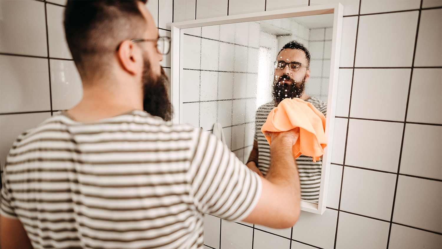 Man cleaning bathroom mirror