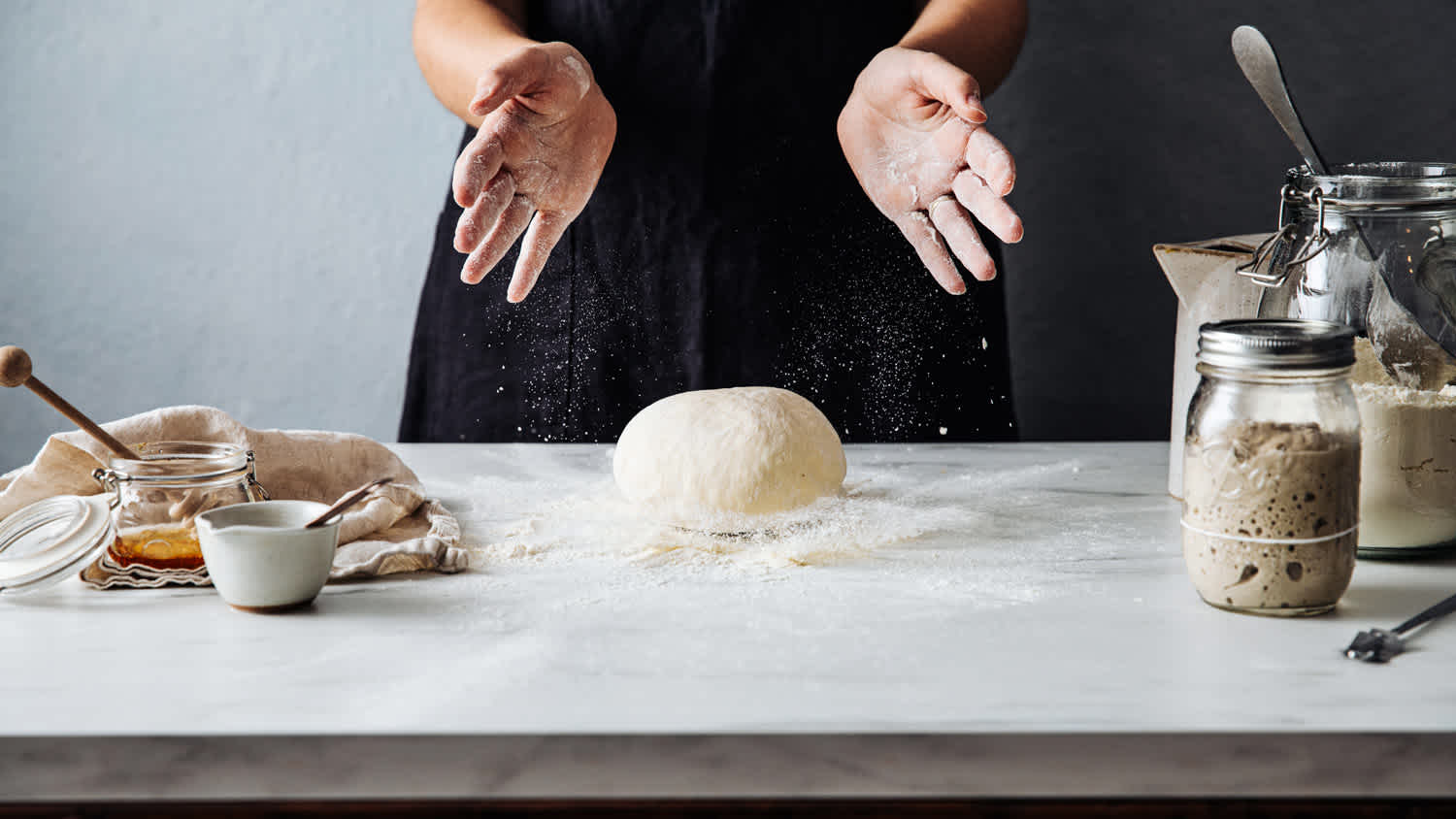 A woman throwing dough on marble countertop