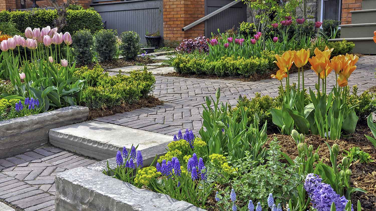 Paver sidewalk to front porch surrounded by beautiful flowers