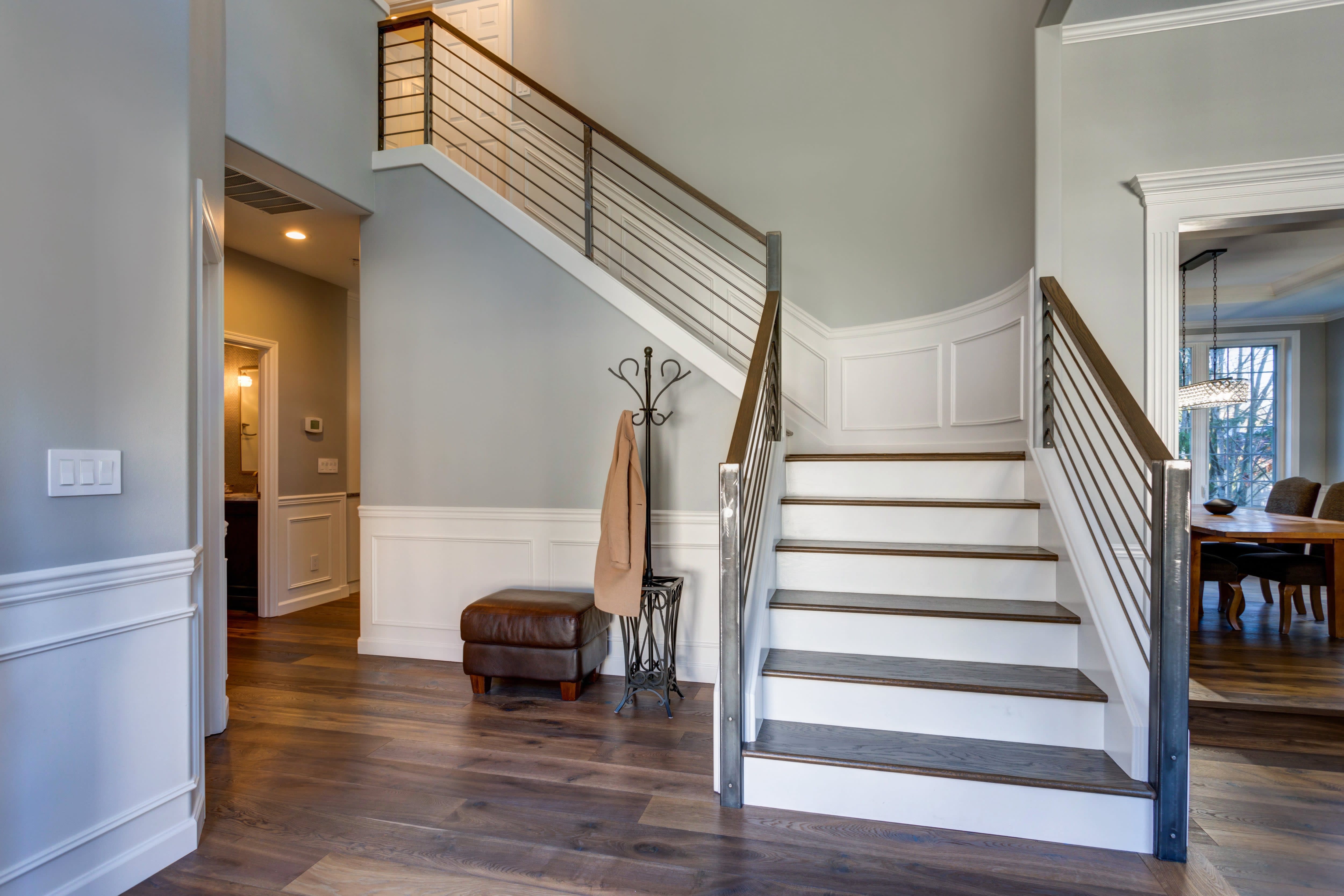 Foyer and staircase with gray walls, white wainscoting, and hardwood floors