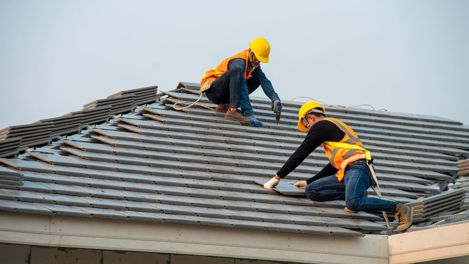 Two roofers installing new ceramic tile roof