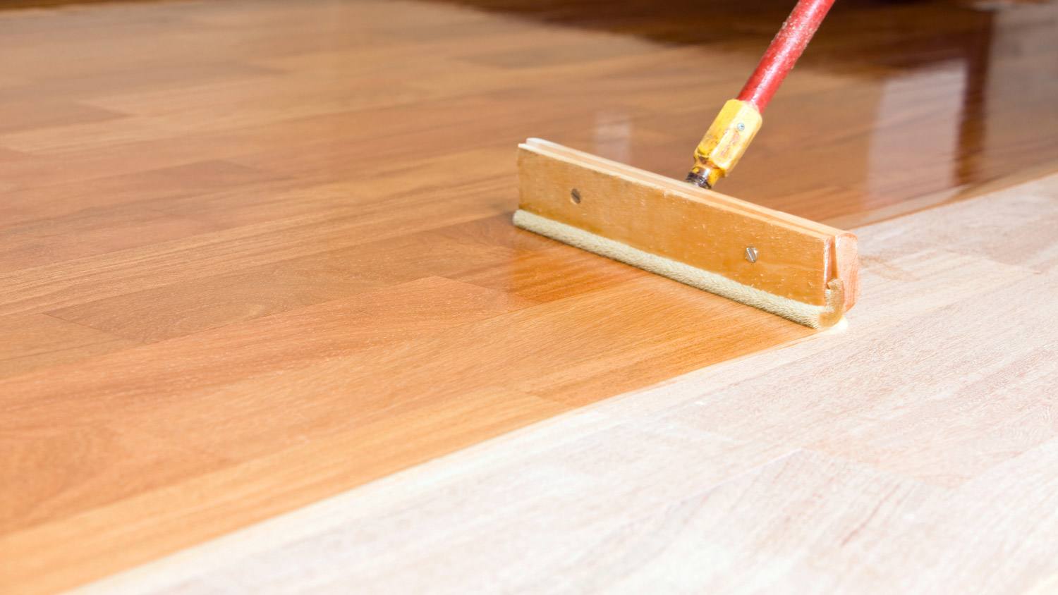 A squeegee bursh applying polyurethane on hardwood floor