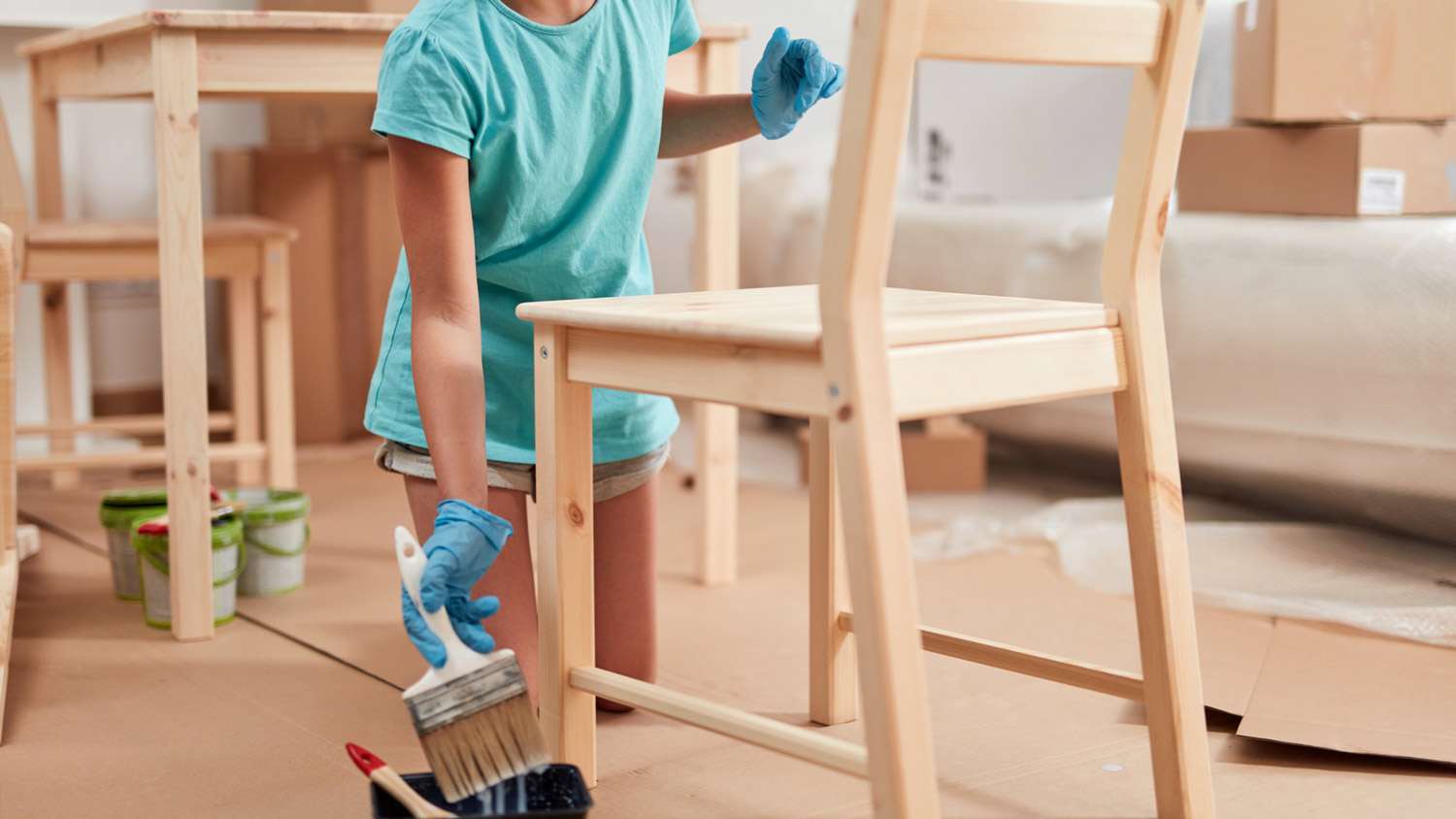 A young woman applying wood sealant on a chair