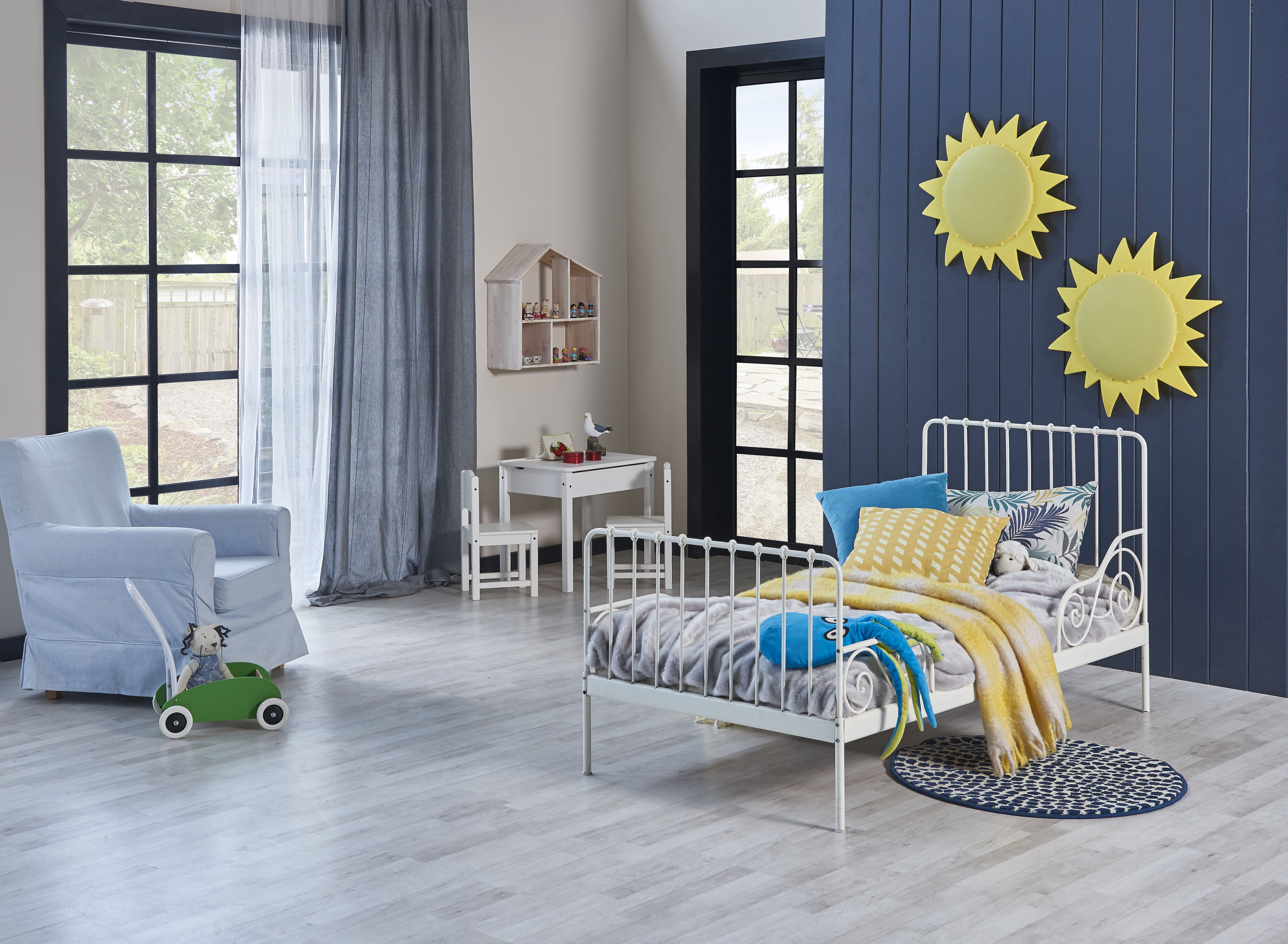 Kids’ room with a toddler bed, armchair, and navy blue vertical shiplap accent wall decorated with yellow suns