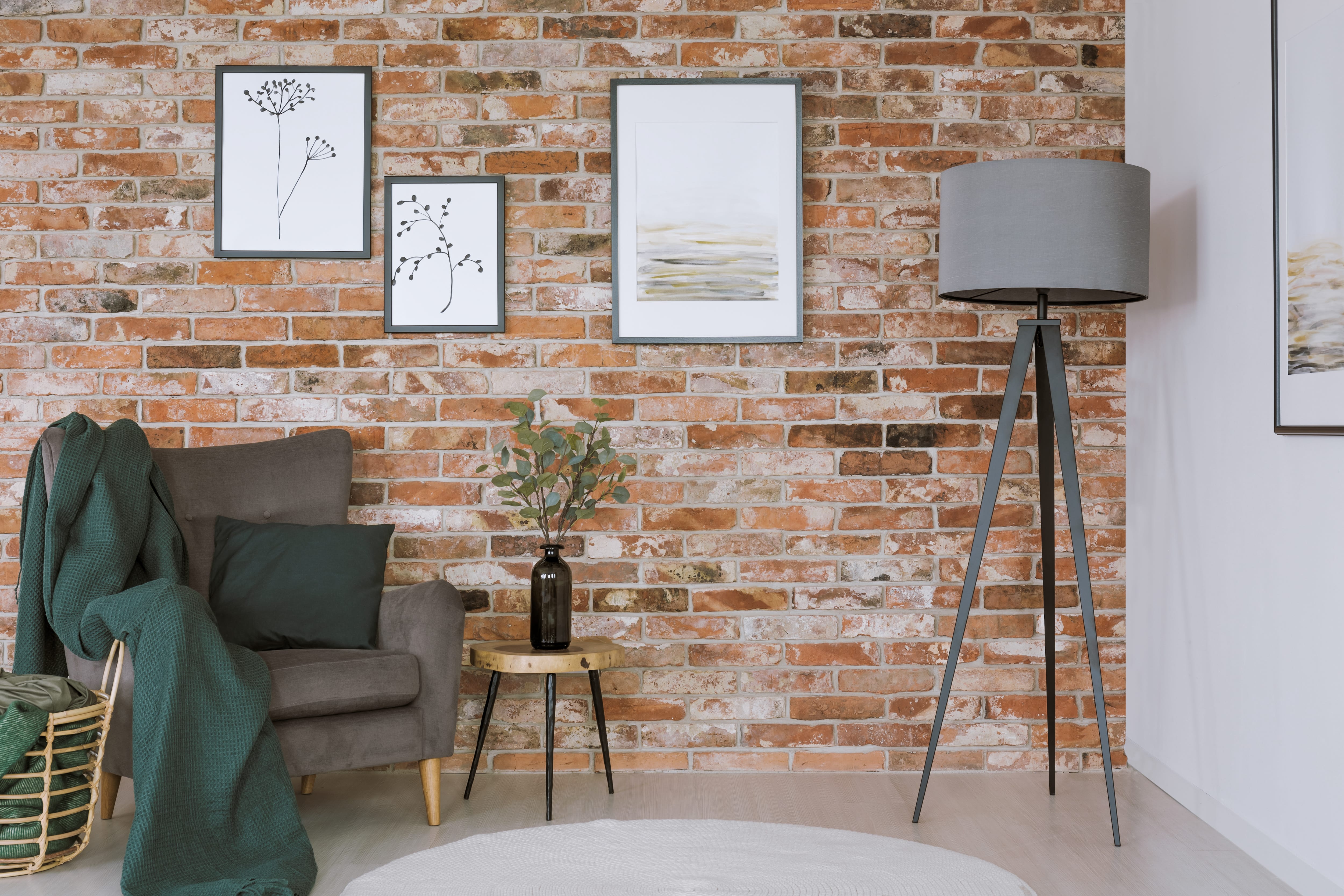 Gray armchair and lamp against red brick wall