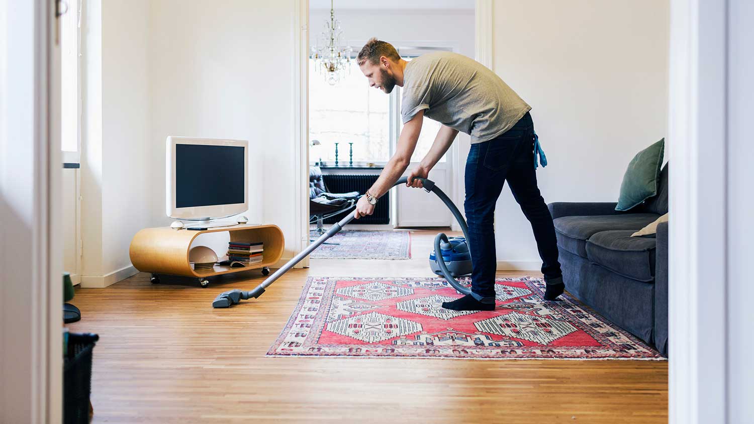 Man using vacuum cleaner to clean hardwood flooring