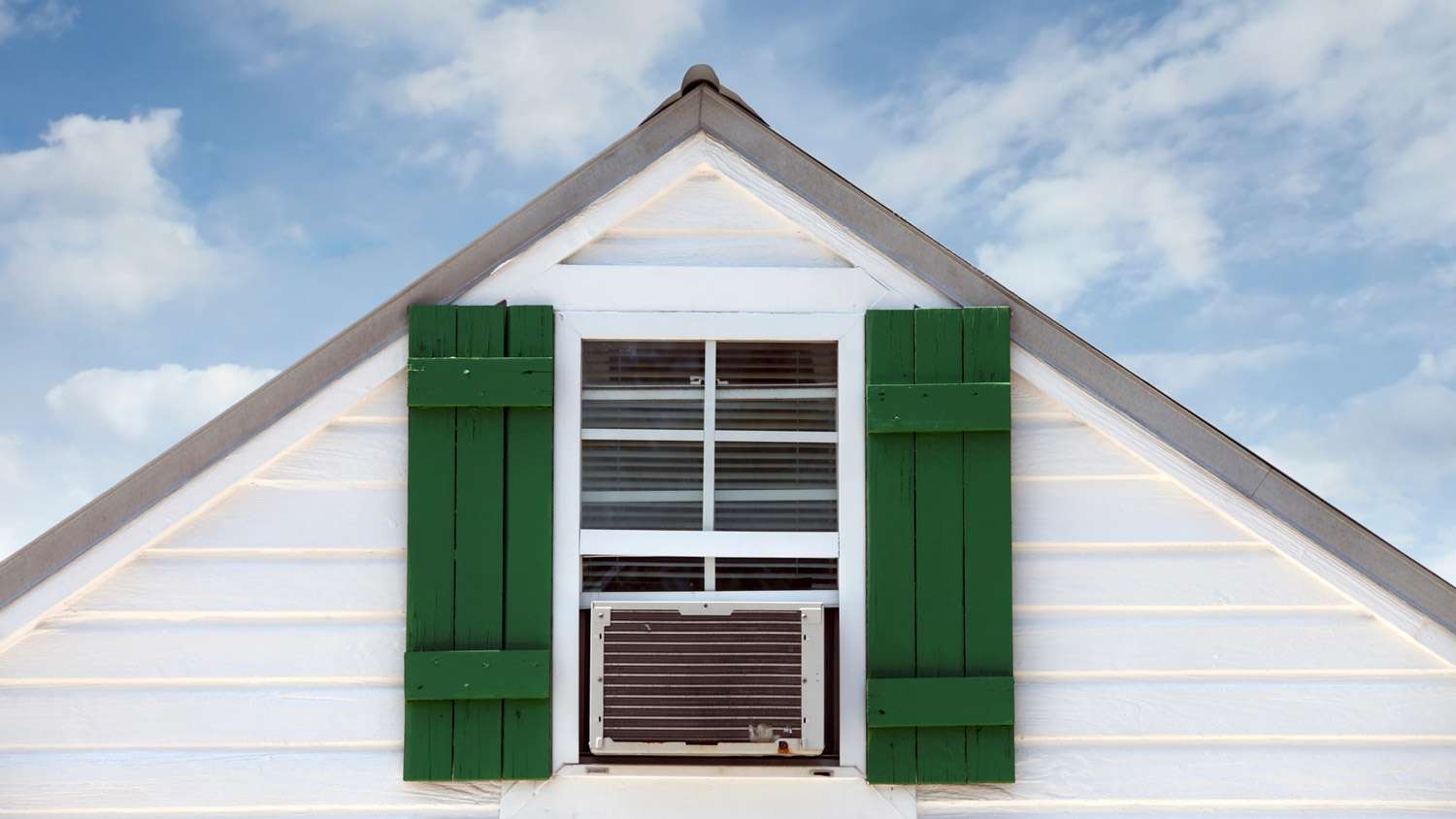 Green painted shutters on a house’s attic window