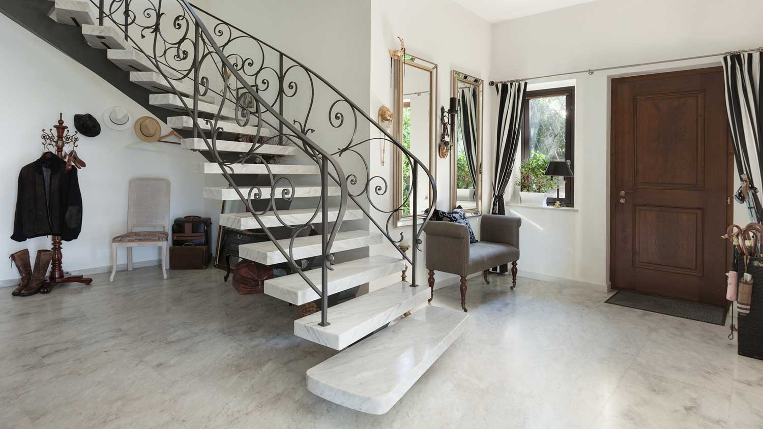 Home entryway with marble floor and curved staircase