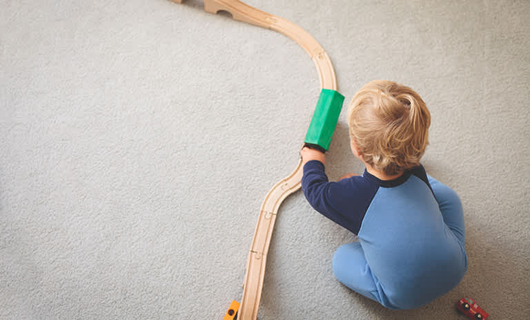 Toddler playing with train on carpet
