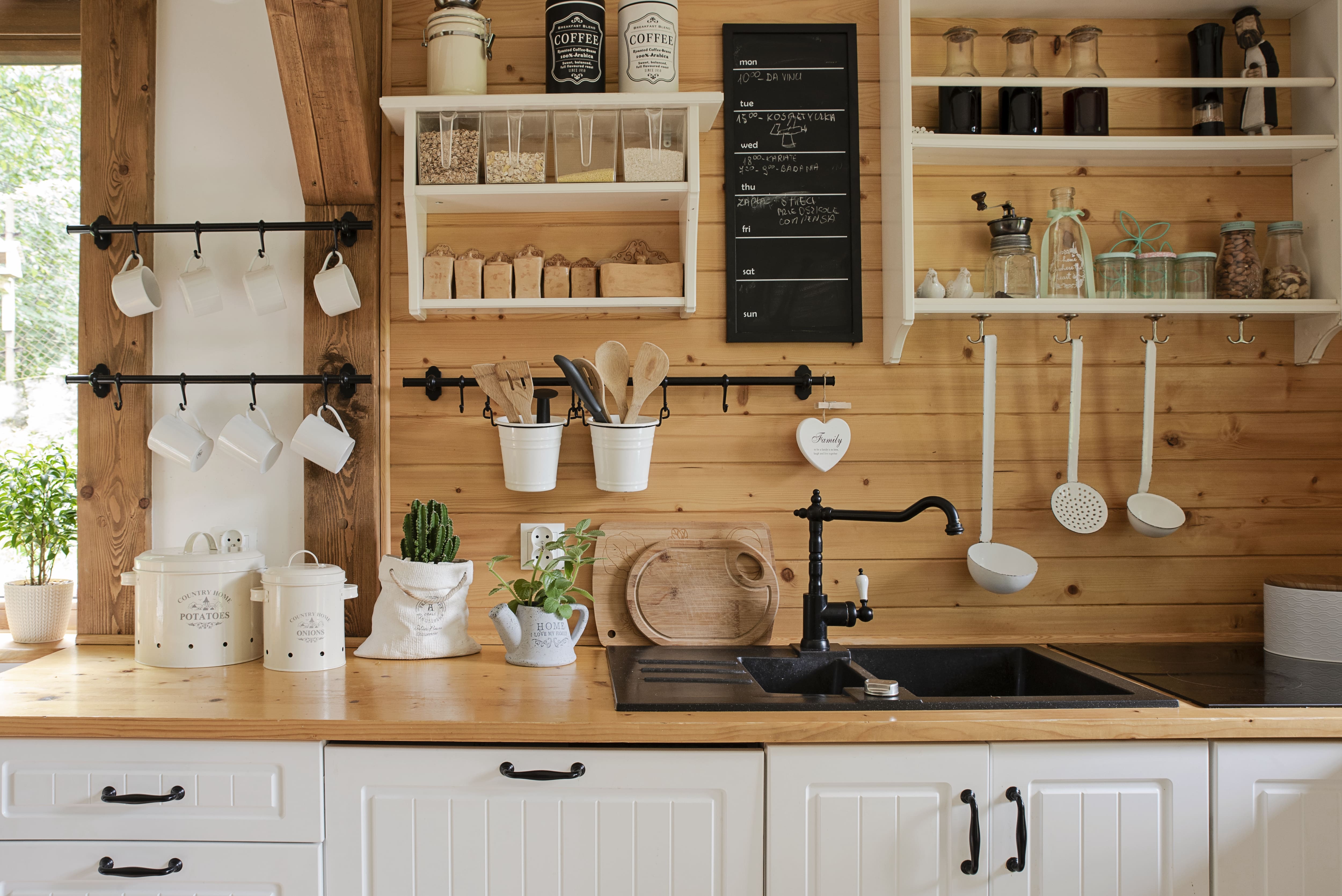 Modern farmhouse kitchen with shiplap wall, white open shelves, white cabinets, and black metal accents