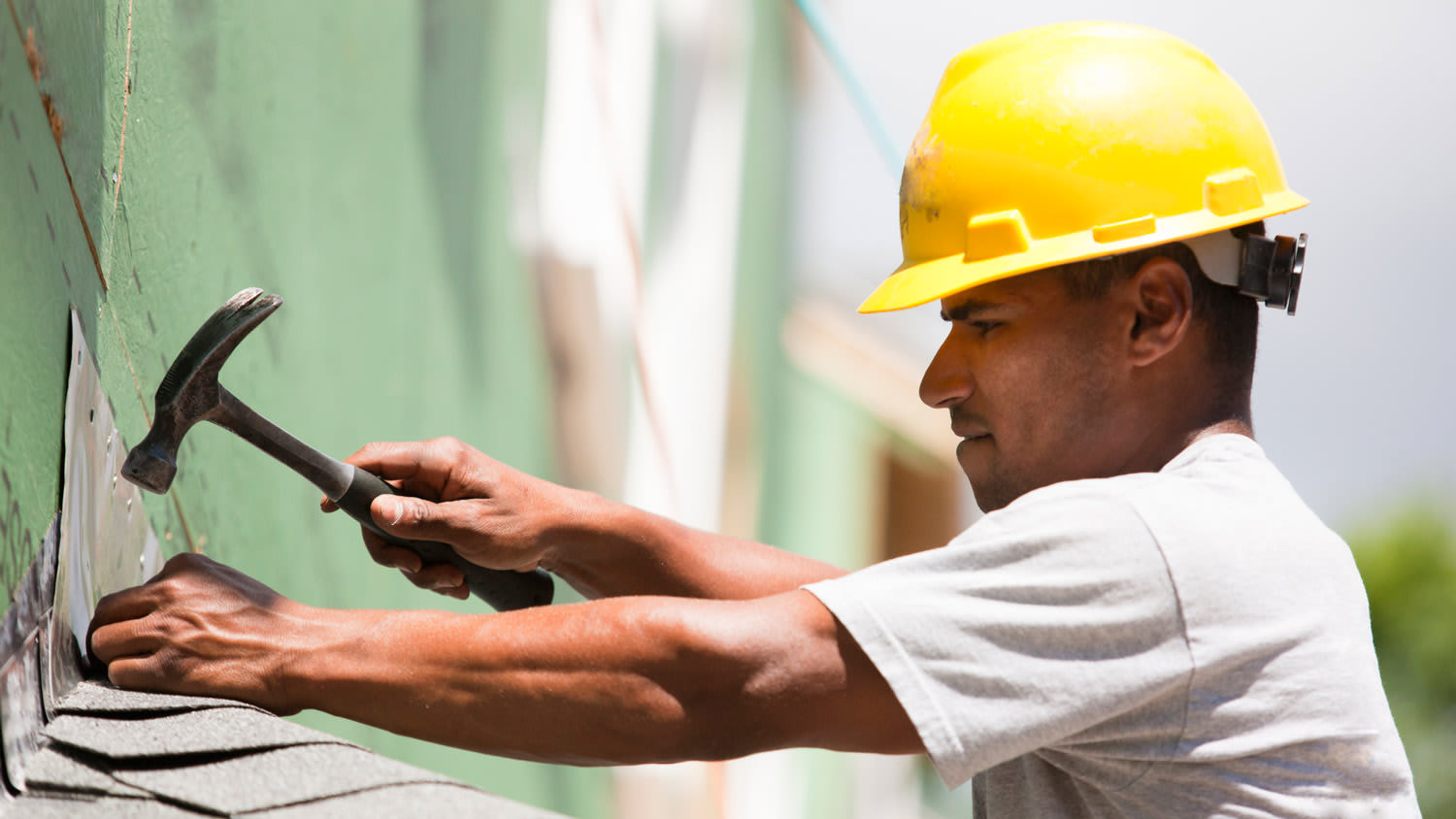A roofer installing new shingles on a roof