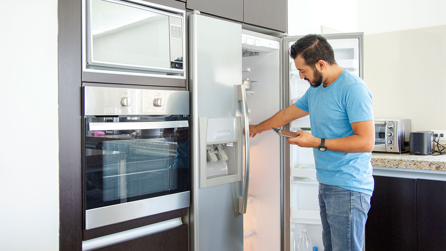 Man in front of the fridge making a shopping list