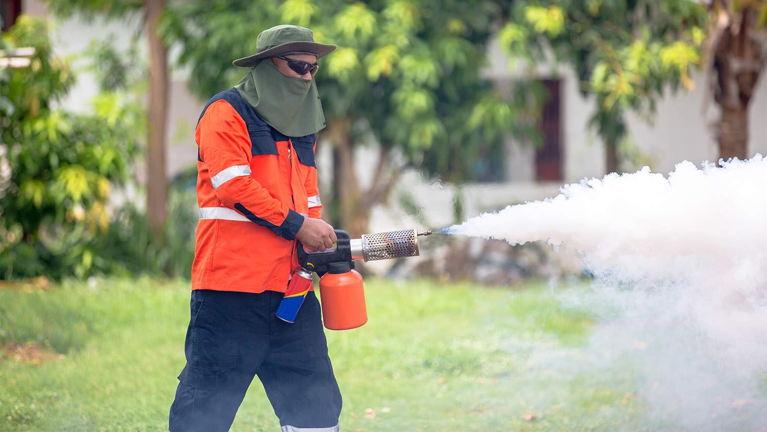 worker spraying insecticides around homes