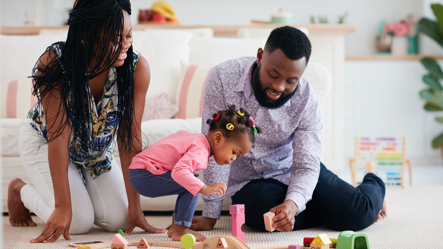 Parents playing with their toddler and a wooden railway