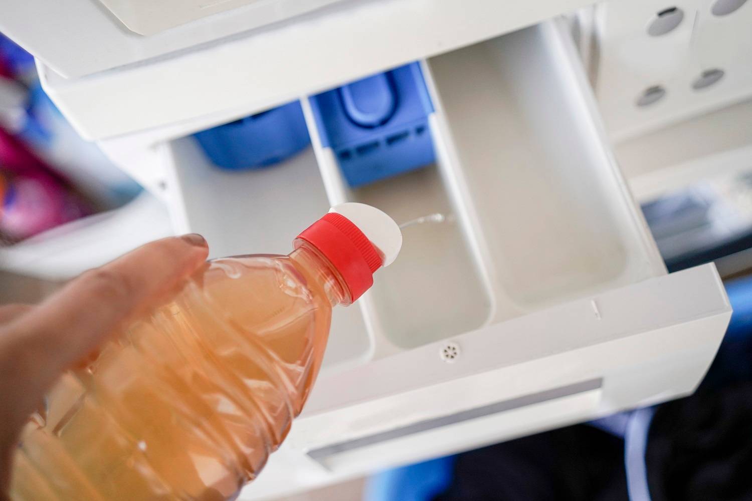 A hand putting vinegar in the washing machine