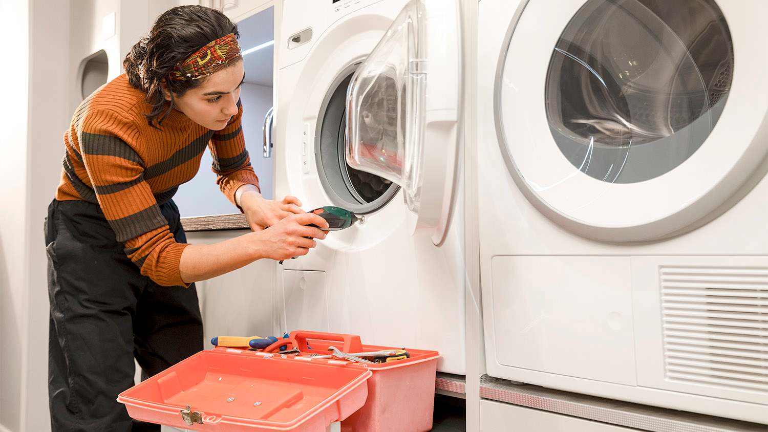 woman repairing washing machine at home