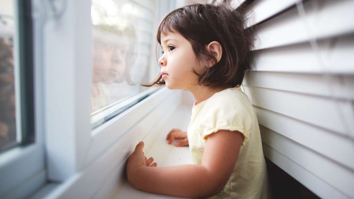 A toddler girl looking out the window