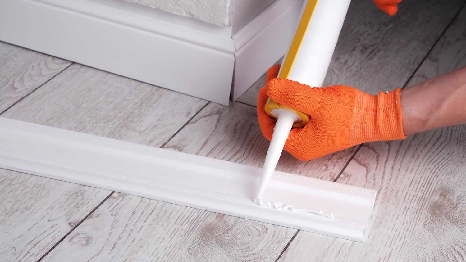 A worker applying glue to skirting board