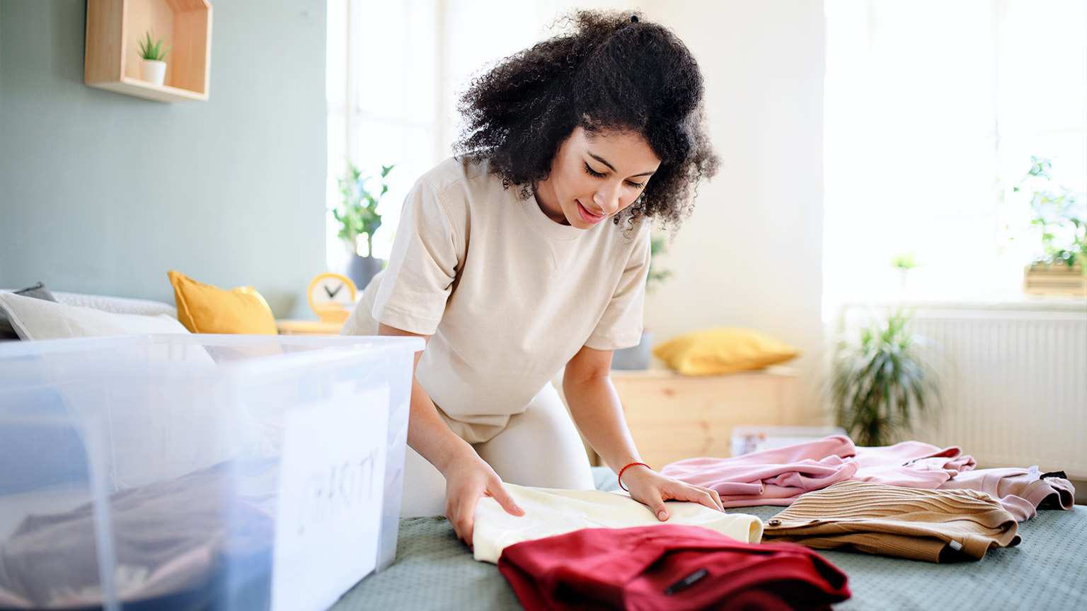 happy woman sorting clothes into charity bin