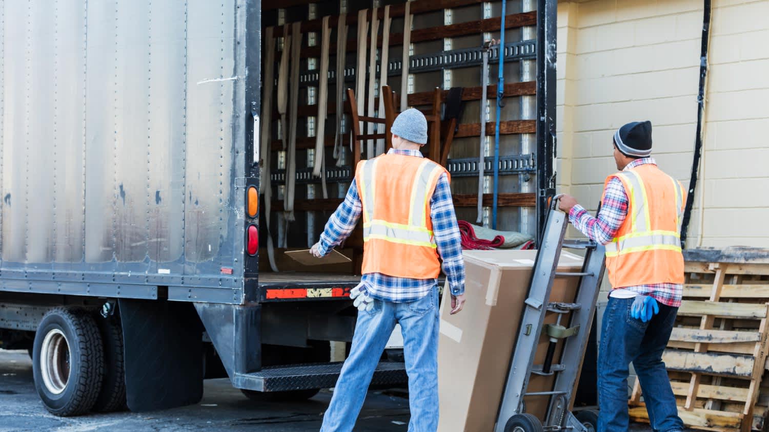 Two workers moving large box