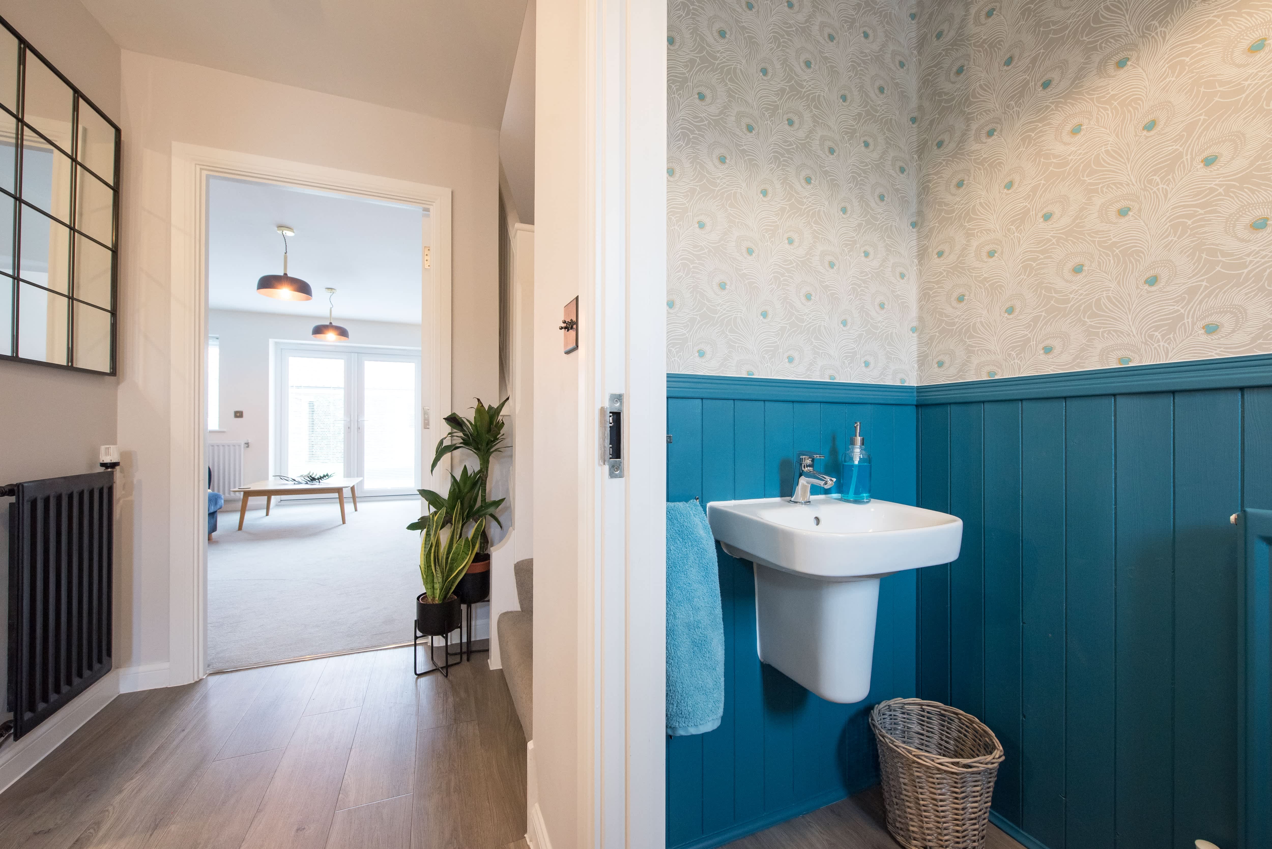 Vintage-inspired powder room with blue wainscoting, patterned wallpaper, and floating sink