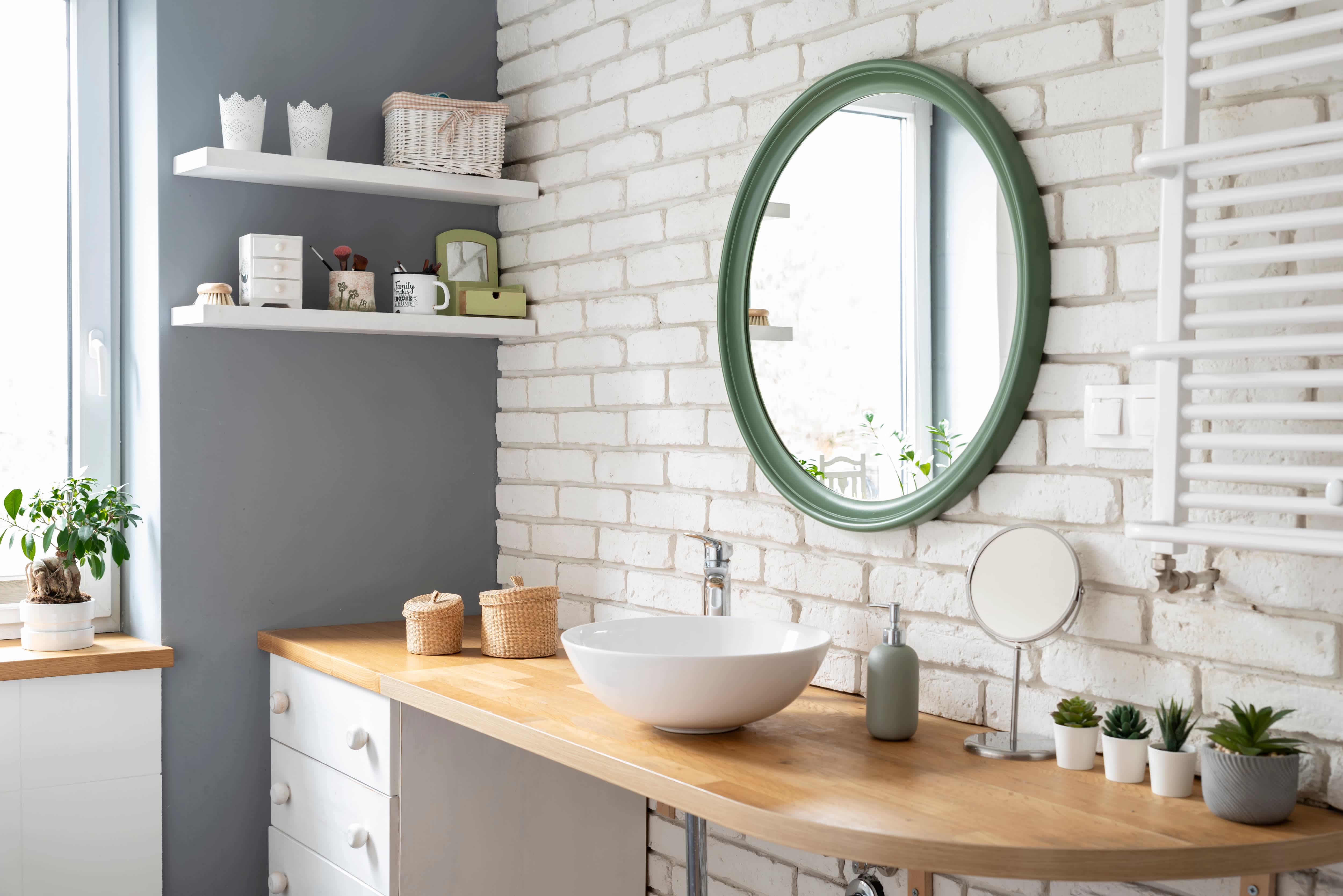 Bright bathroom with exposed brick walls, plants, a hexagonal mirror, and wooden plants