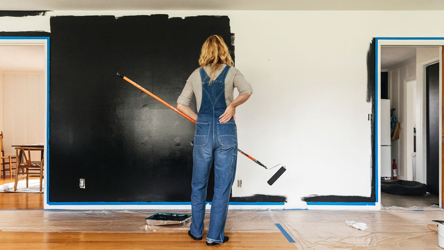 Woman painting a wall with black paint