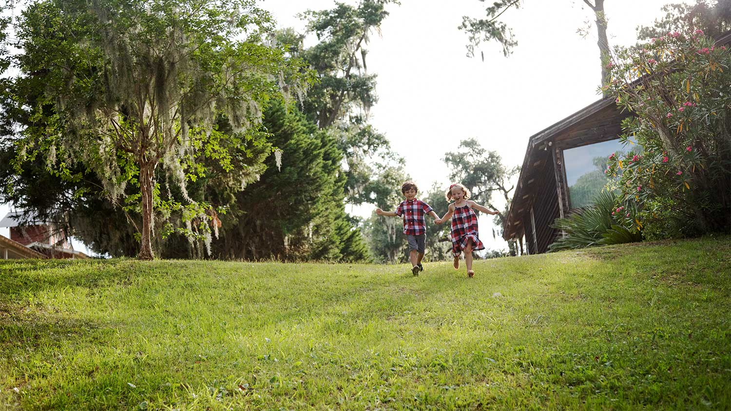 Two children walk down a backyard hill