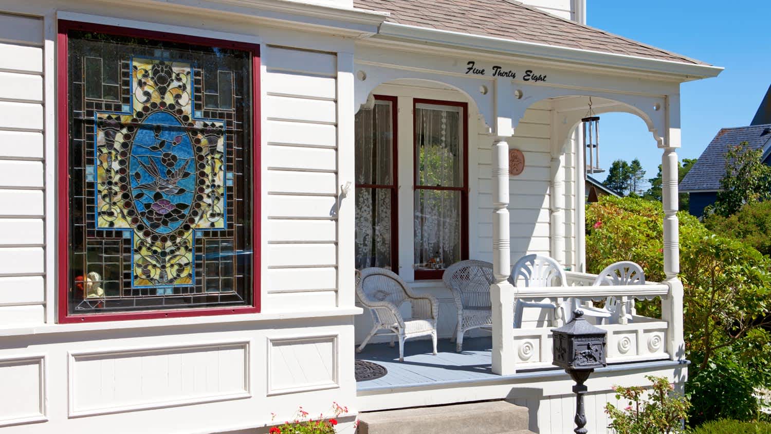 The exterior of a white house with a gorgeous stained glass window