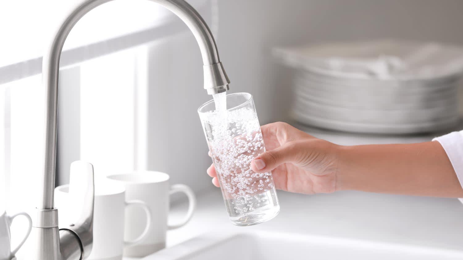Woman pouring water into glass in kitchen