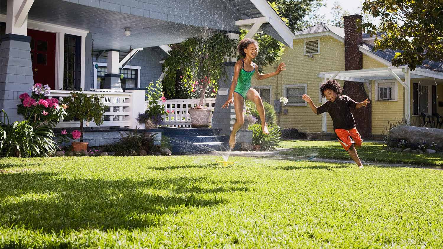 Kids running through lawn sprinkler