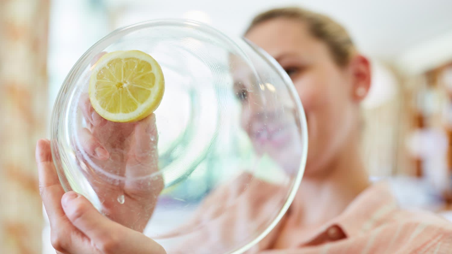 A woman cleaning glass bowl with lemon