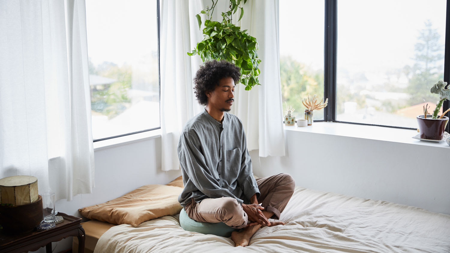 A man meditating with his eyes closed on his bed