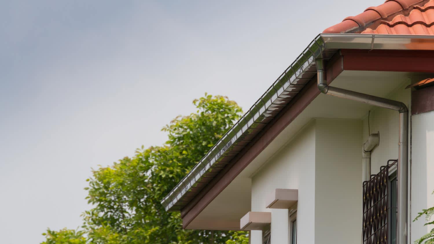 Steel rain gutter with downpipe on the house roof