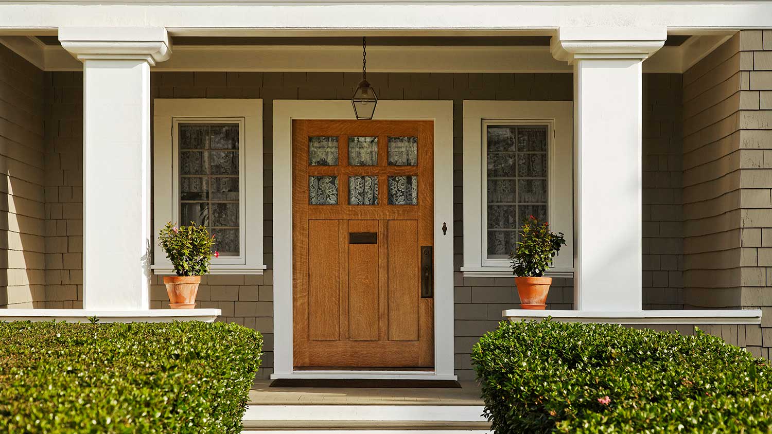 House main entrance with wooden door and bushes