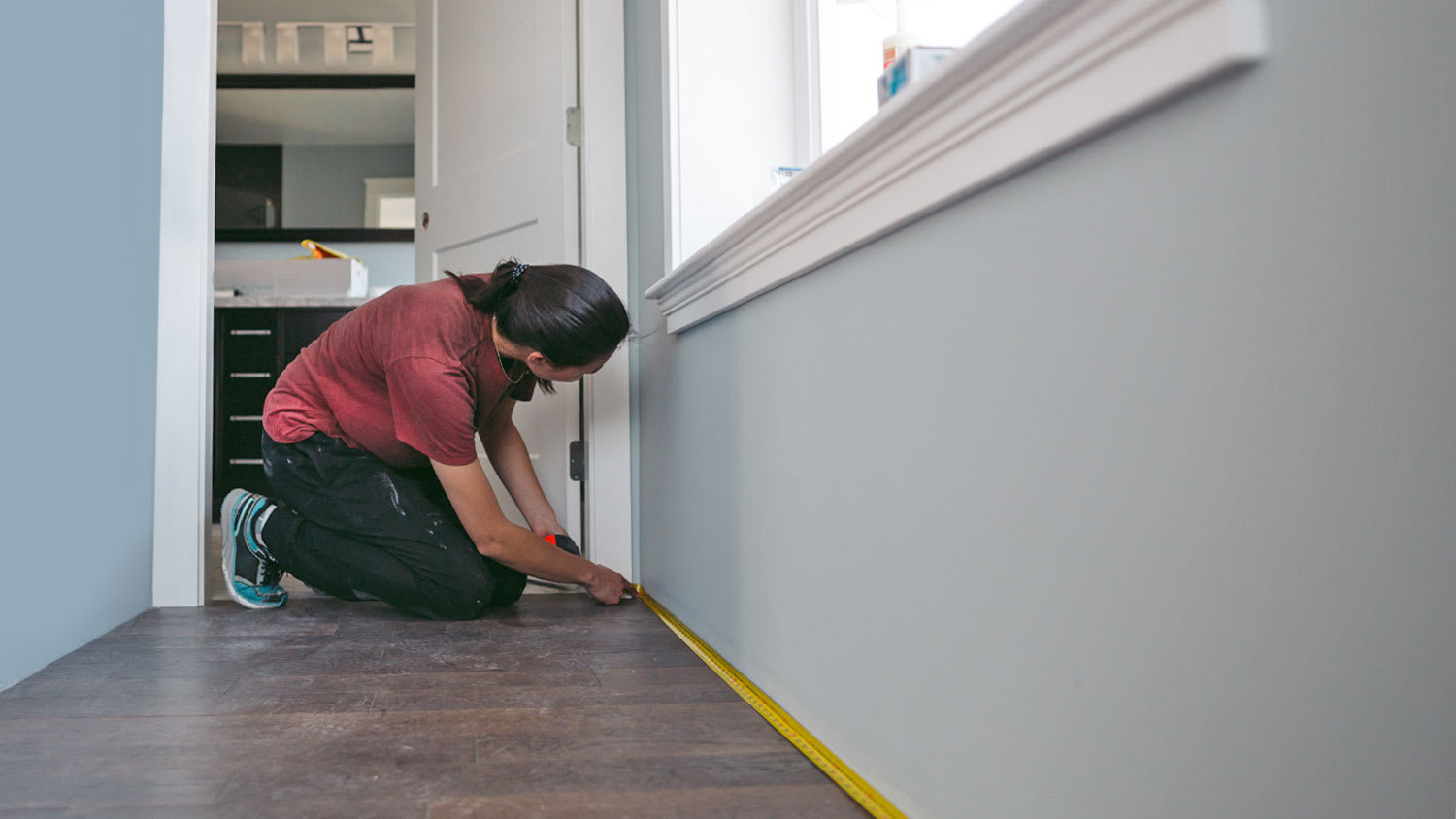 woman measuring baseboard for heater