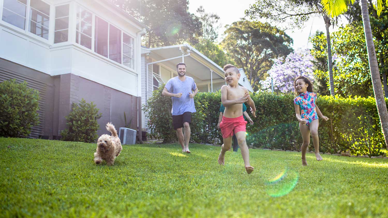 Family running in the yard with their pet