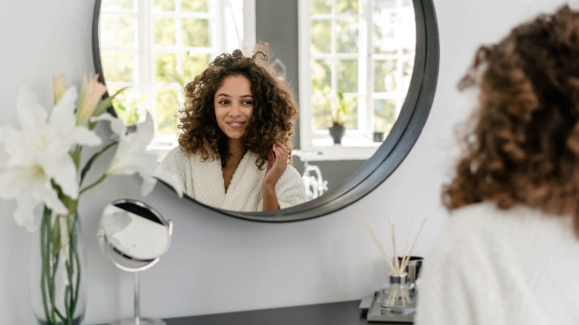 woman looking at her hair in the mirror